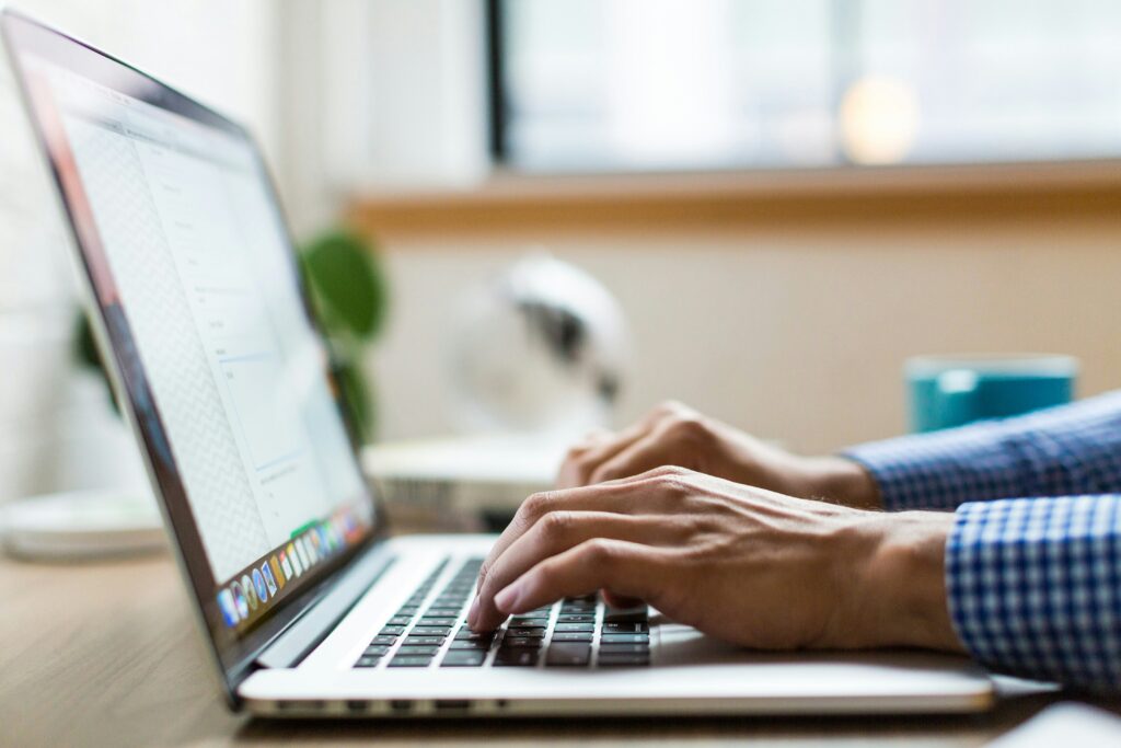 A person typing on a MacBook laptop, representing searching for image sources and performing reverse image searches on Tumblr.