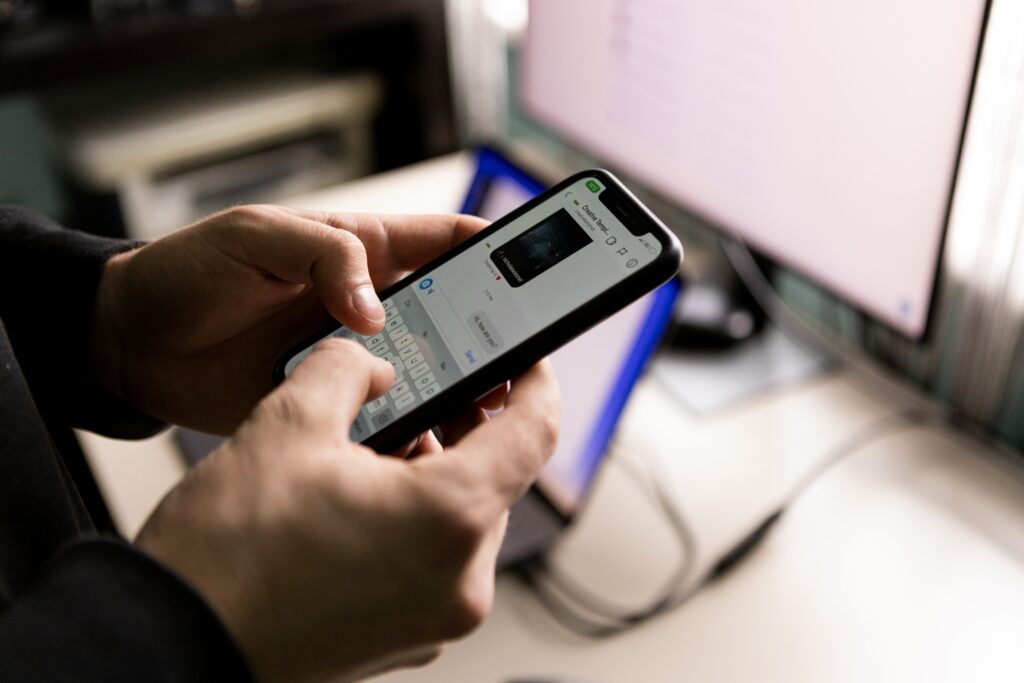 A person holding a smartphone showing a messaging app conversation with a photo shared in chat, representing how to reverse image search a photo received on WhatsApp to verify who sent it.