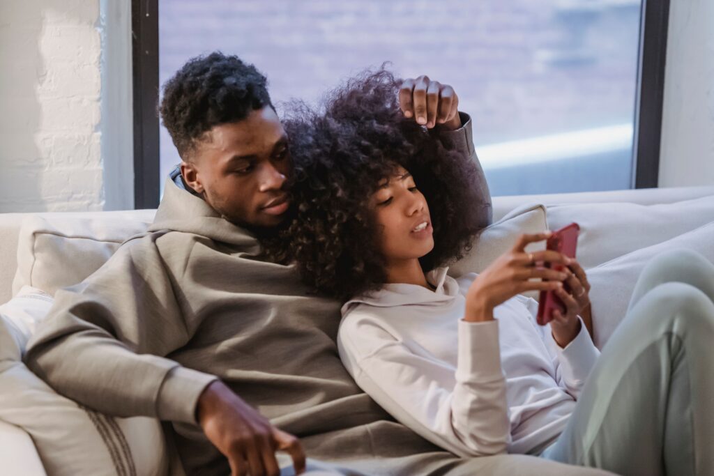 Couple sitting together on couch looking at phone — does my girlfriend have an OnlyFans account