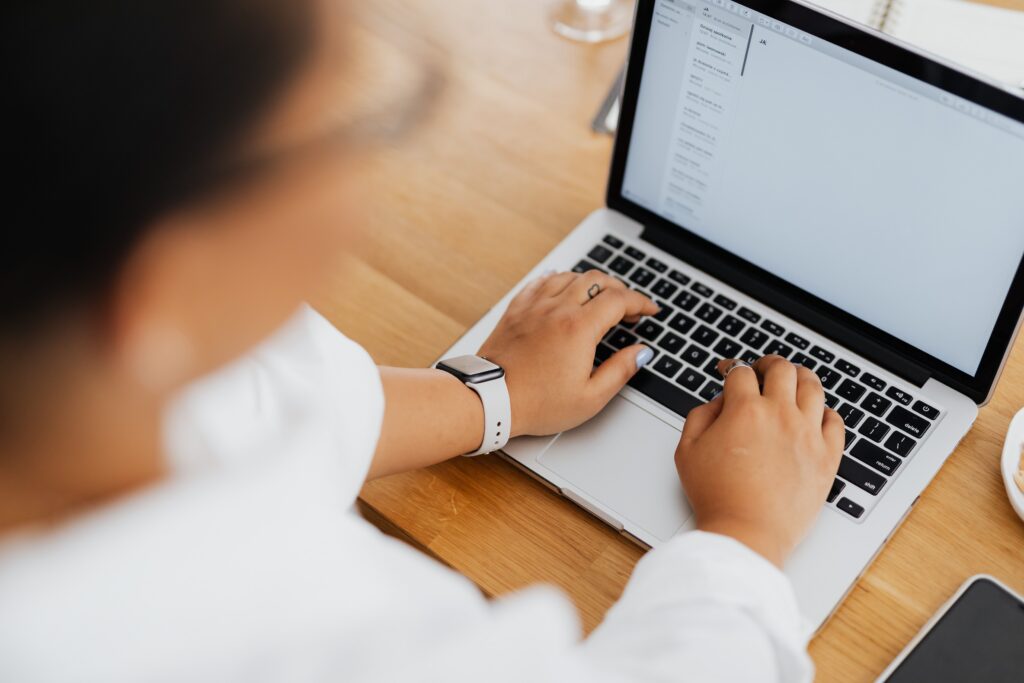 Close-up of hands typing on a laptop keyboard with an email inbox open on screen