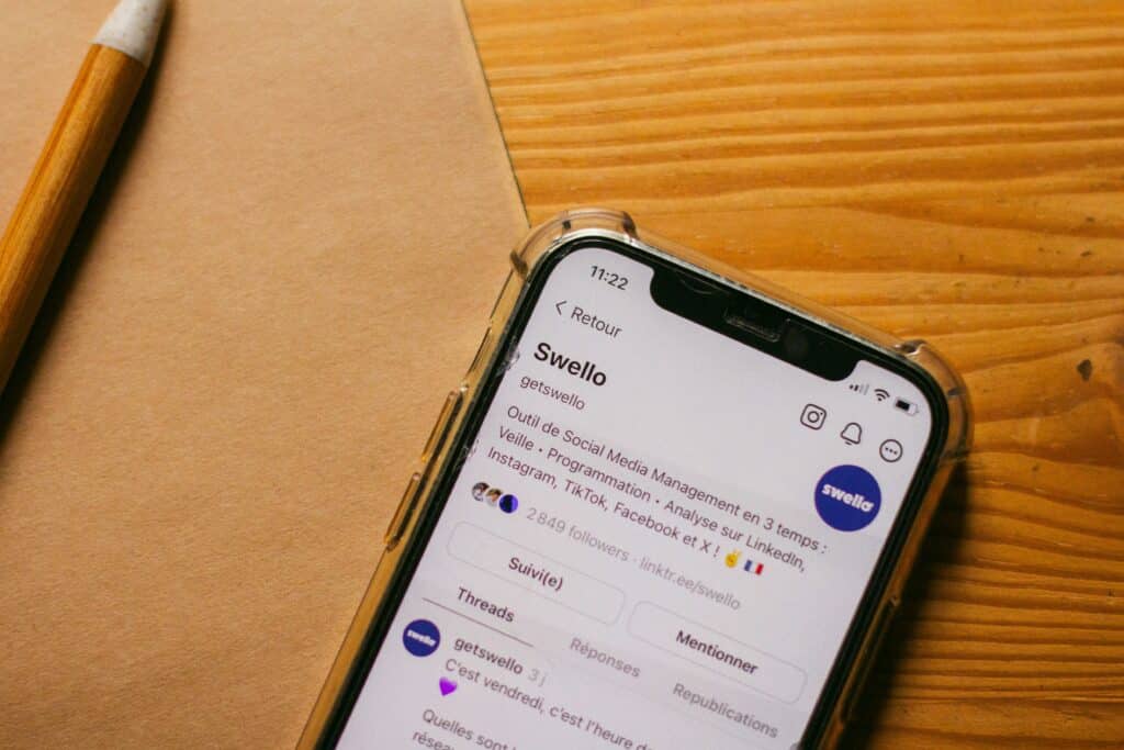 Close-up of a phone screen showing the Swello brand's Threads profile with follower count and bio