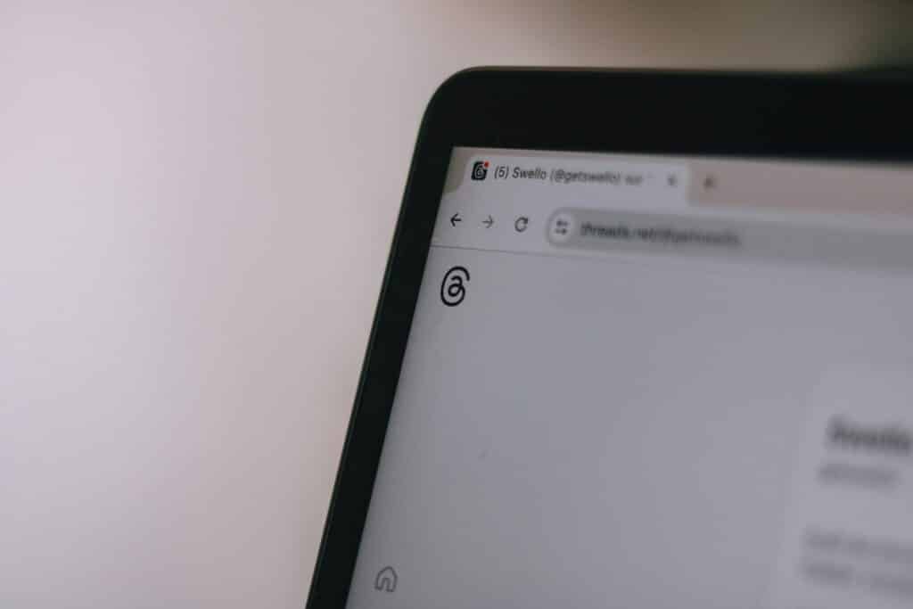 Close-up of a laptop browser tab open to a Threads profile page, showing the Threads logo