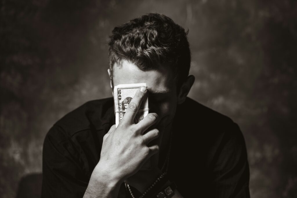 Person hiding face behind cash — sugar daddy scam warning signs and how to spot a fake sugar daddy