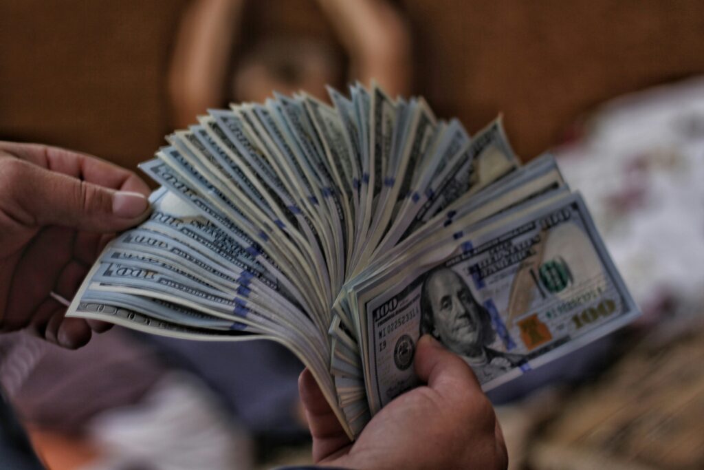 Hands holding a large amount of cash — how sugar daddy scams promise money before stealing from victims