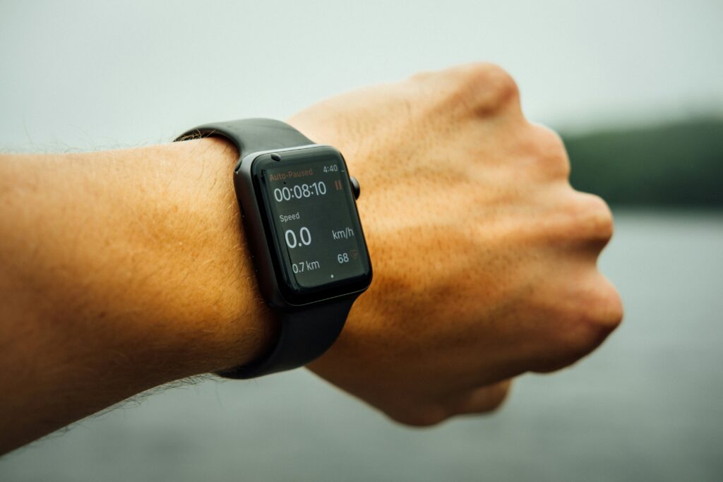 Person wearing a smartwatch tracking a run, showing time, speed, and heart rate