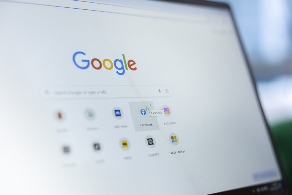Close-up of a laptop screen showing the Google homepage with a cursor hovering over the Facebook shortcut icon, Instagram icon visible alongside it